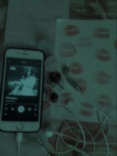 a cell phone sitting on top of a table next to ear buds and an mp3 player