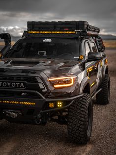 a black toyota truck with yellow lights on it's front bumpers and tires