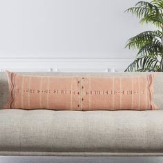 a beige couch sitting next to a potted plant