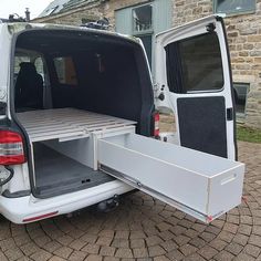 the back end of a white van with its cargo door open on a cobblestone driveway