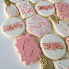 decorated cookies with pink and white icing on a table next to gold trimmings