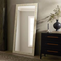 a mirror sitting on top of a dresser next to a vase