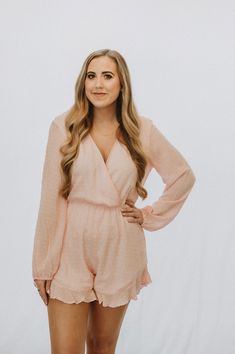 This is a pink long sleeve romper with a v neck and a keyhole back. The model is wearing a size medium. Feminine V-neck Jumpsuits And Rompers For Night Out, Spring Long Sleeve Jumpsuits And Rompers For Night Out, Casual Pink Jumpsuits And Rompers For Date Night, Casual Pink Jumpsuits For Date Night, Chic Long Sleeve Jumpsuits And Rompers For Brunch, Chic Long Sleeve Jumpsuits For Brunch, Long Sleeve Jumpsuits And Rompers For Brunch, Chic Long Sleeve Jumpsuits And Rompers For Loungewear, Long Sleeve Jumpsuits And Rompers For Spring Brunch