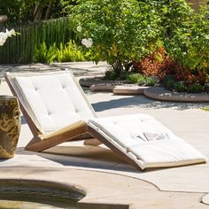 an empty lounge chair sitting on the ground next to a water fountain and flower pot