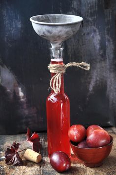 a glass bottle with some fruit in it and a bowl on the table next to it