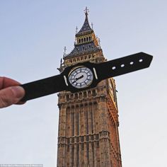 a person holding up a piece of paper with a clock on it in front of the big ben tower