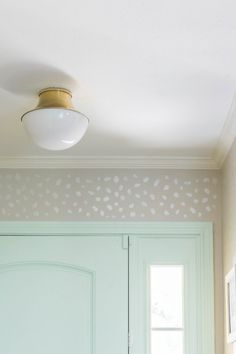 a green door with white paint on it and a light fixture over the front door