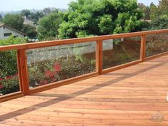 a wooden deck with glass railing and flowers