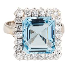 This is part of Chairish’s Fine Jewelry assortment.  Stylish and finely detailed aquamarine & diamond ring crafted in 18 karat white gold (circa 1970s to 1980s).  Emerald cut aquamarine measures 11.9 x 10.5 x 6.5mm (estimated at 5.35 carats). Diamonds total an estimated 0.65 carats (estimated at H-I color and VS2-SI2 clarity). The aquamarine is in very good condition and free of crack or chips.   The clear as sky blue emerald cut aquamarine is framed with shimmering diamonds. The square cocktail Vintage Solitaire Engagement Ring, Vintage Gold Engagement Rings, Square Diamond Rings, Cocktail Jewelry, Gold Cocktail Ring, Gold Cocktail, 18k Gold Ring, Square Rings, Ring Crafts