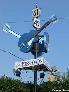 a street sign with a guitar hanging from it's side