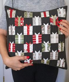 a woman is holding a pillow made out of christmas wrappings and presents on it