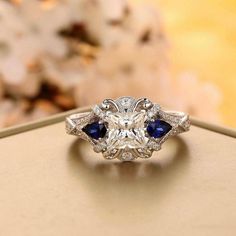 a diamond and blue sapphire ring sitting on top of a table