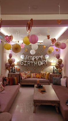 a living room filled with lots of furniture and balloons hanging from the ceiling above it