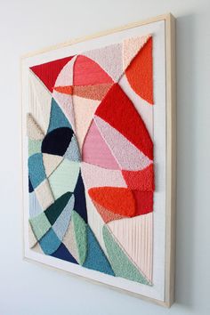 an art piece hanging on the wall next to a white wall with red, blue and green shapes