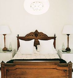 a bed with two lamps on either side of it and a white wall in the background