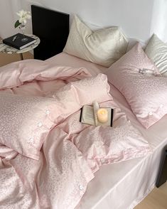 a bed with pink sheets, pillows and a book on it's headboard