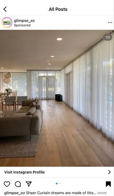 a living room filled with furniture and windows covered in white sheer curtained drapes