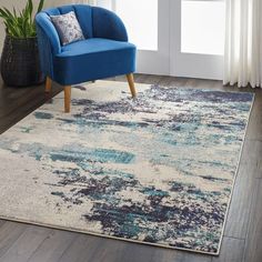 a blue chair sitting on top of a wooden floor next to a white and blue rug