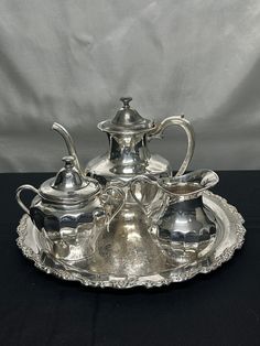 a silver tea set on a black table