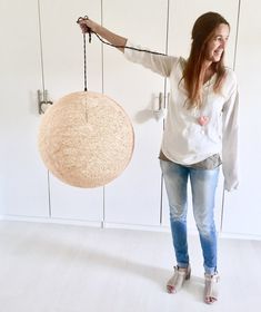 a woman holding a round object in one hand and another hanging on the other side