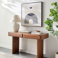 a table with two books and a lamp on it in front of a white wall