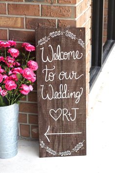 a wooden sign that says, welcome to our wedding art next to pink carnations