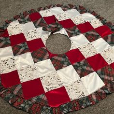 a red and white quilted christmas tree skirt on the floor in front of a carpet