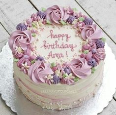 a birthday cake with pink frosting and purple flowers