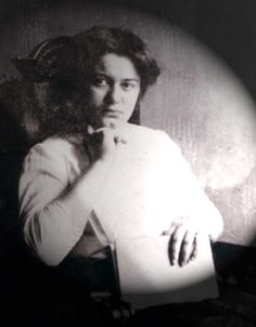 an old black and white photo of a woman with her hand on her chin looking at the camera