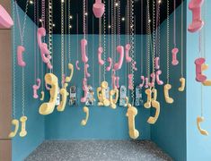 a room filled with pink and yellow telephones hanging from the ceiling next to blue walls