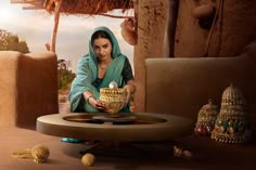 a woman is holding a bowl in front of a table with an ornate decoration on it