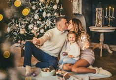 a man, woman and child sitting in front of a christmas tree