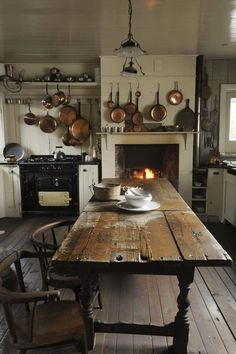 a kitchen with an old table and oven in the center, surrounded by pots and pans