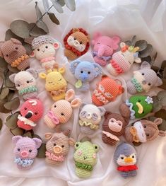 small crocheted stuffed animals are arranged in a circle on a white cloth with leaves