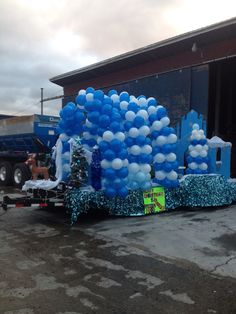 blue and white balloons are on the back of a trailer in front of a building