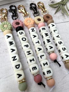 four key chains with words and flowers on them, all in different shapes and sizes