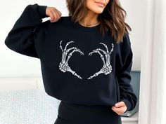 Skeleton hands heart sweatshirt. Perfect for Halloween and Valentine's Day. UNISEX SWEATSHIRT 50% Cotton / 50% Poly Fleece Drop shoulder and relaxed fit Runs true to size Size up for a baggier Heart Sweatshirt, Heart Sweater, Heart Hands, Skeleton Hands, Emo Goth, L And Light, Halloween Sweatshirt, Military Green, Black Charcoal