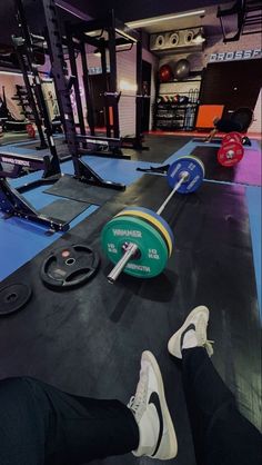 a person with their feet on the ground in front of a barbell and weight plate