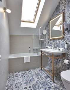 a bathroom with blue and white tiles on the floor, sink, mirror and bathtub