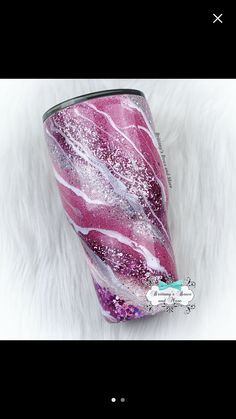 a pink and white tumbler cup sitting on top of a fur covered floor with glitter