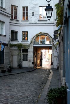 an alley way with a lamp post in the middle and buildings on both sides,