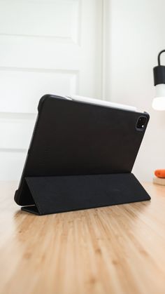 an ipad case sitting on top of a wooden table next to a lamp and carrots