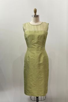 "Vintage-inspired sheath style with illusion top.  -Jewel neckline sleeveless silk organza illusion top with single button & loop back closure -Fitted sheath style with 1\" waistband detail -Below the knee length (can be customized) -Center back vent for ease of movement -Invisible center back zipper Shown in Spring Green.  Fabrics: Silk Shantung, silk organza, poly China silk lining Dry clean only. This style is available made-to-order. Please see instructions below. This dress needs to be fit quite precisely, so you should expect to do a little tailoring to achieve a perfect fit.  We recommend providing your measurements even if you are ordering a standard size.  MADE TO MEASURE Available custom made-to-measure with choice of fabrics and colors. The price varies depending on size and fab Fitted Green Dress With Illusion Neckline, Fitted Silk Dress With Sheer Back, Green Fabrics, Shantung Silk, Illusion Top, Be Fit, Jewel Neckline, Silk Organza, Spring Green