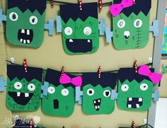 some paper bags with faces and eyes hanging on a line in front of a bulletin board