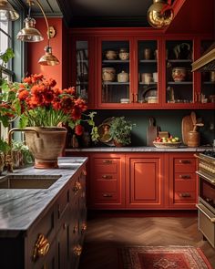 a kitchen with red cabinets and flowers in vases on the counter top next to an oven