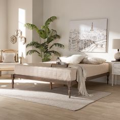 a bedroom with white walls and wooden floors, a bed in the foreground has a plant on top of it