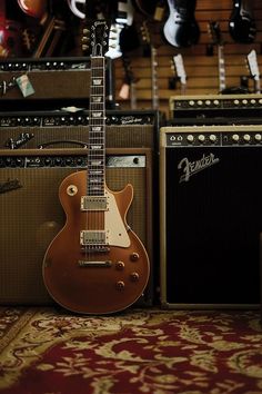 an electric guitar sitting on top of a carpet next to amps