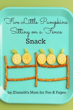 a blue plate with crackers and pumpkins sitting on a fence made from pre - k pages