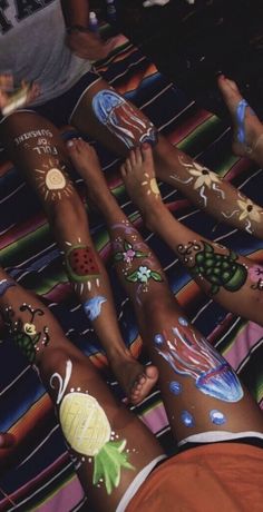 several people with their hands painted in different colors and designs on their legs, all holding onto each other's arms