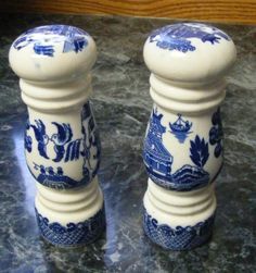 two blue and white salt and pepper shakers sitting on a marble counter top next to each other